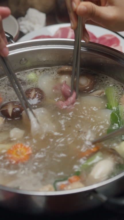 Gryte med varm suppe, grønnsaker og kjøtt som deles ved bordet